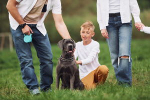 Sitting on the ground with dog. Family have weekend outdoors at summertime together